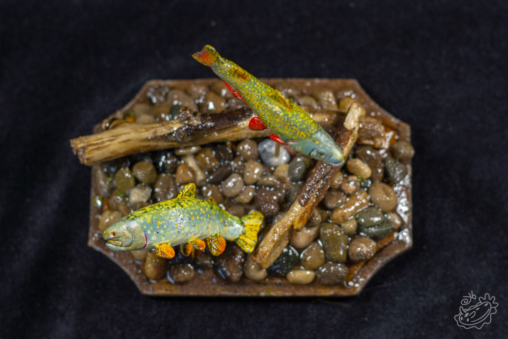 A model of two Brook Trout. The male swimming above and the female below creating a nest in the pebbles. View From Above.