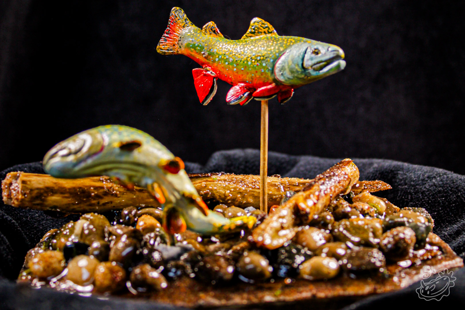 A model of two Brook Trout. The male swimming above and the female below creating a nest in the pebbles. Front View.