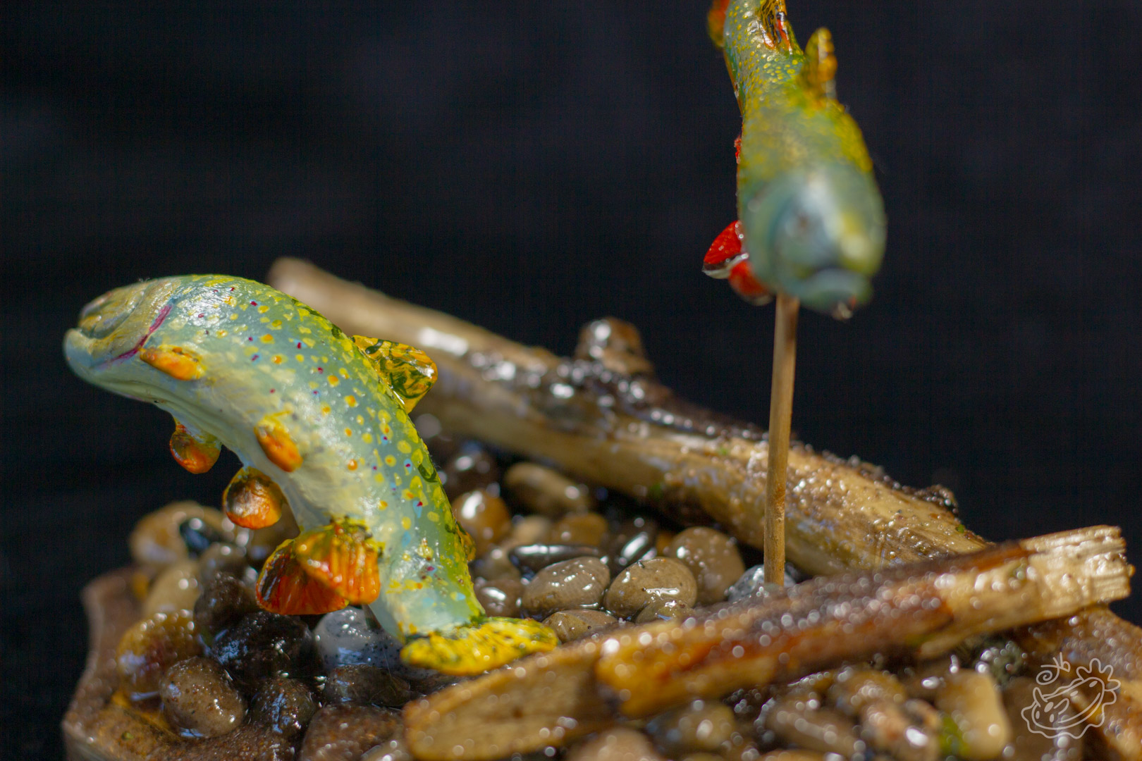 A model of two Brook Trout. The male swimming above and the female below creating a nest in the pebbles. Tight Side View.