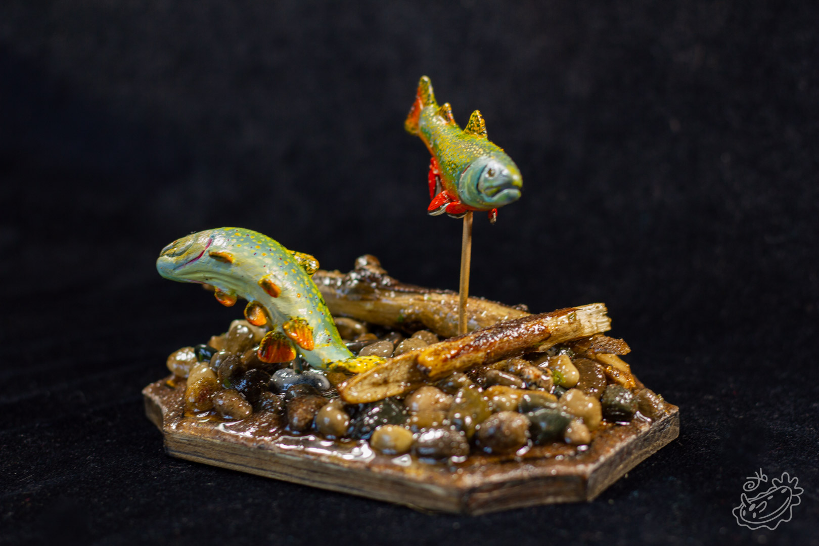 A model of two Brook Trout. The male swimming above and the female below creating a nest in the pebbles. Wide Side View.